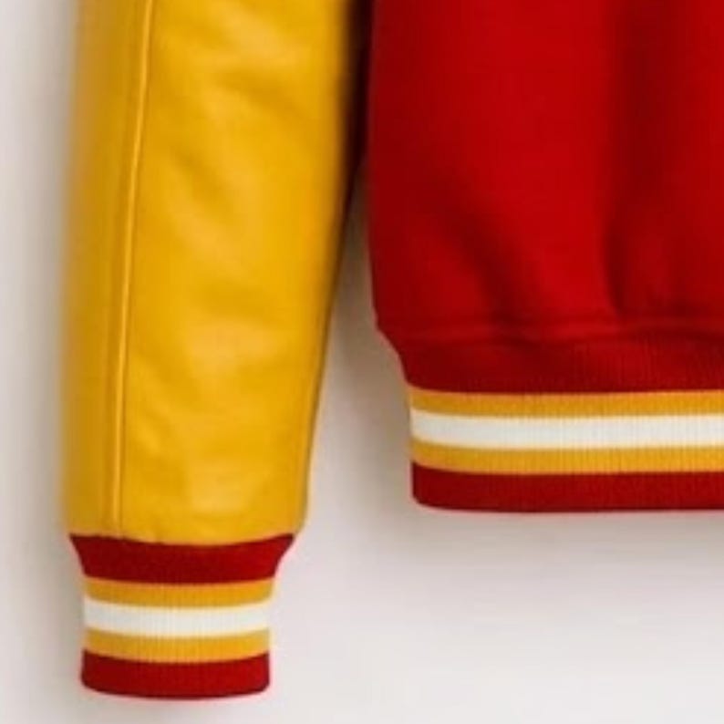 Puede incluir: Una chaqueta universitaria con cuerpo de mezcla de lana en color rojo brillante y mangas de piel sint&eacute;tica en amarillo contrastante. La prenda incluye pu&ntilde;os y dobladillo de punto acanalado con un patr&oacute;n de rayas en rojo, amarillo y blanco.