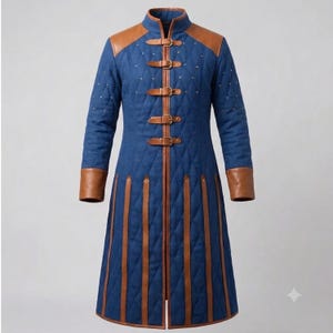 May include: A long blue quilted coat featuring brown leather trim on the shoulders and cuffs. The front closure consists of four brown leather straps with metal buckles. Vertical brown leather strips extend from the waist to the hemline.