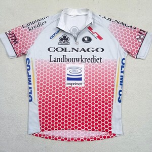 May include: A short-sleeved cycling jersey featuring a white and red honeycomb pattern. The front displays the text Colnago, Landbouwkrediet, Olympus, and Esprinet. It has a quarter-zip collar and various sponsor logos printed across the chest and sleeves.