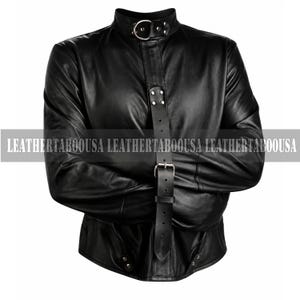 May include: Black leather jacket with a high collar and a strap across the chest. The jacket has long sleeves and a buckle closure. The text "LEATHERTABOUSA" is printed across the bottom of the image.