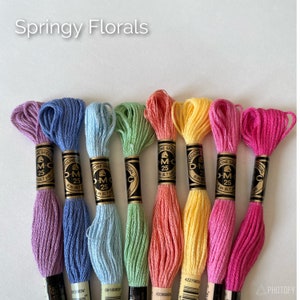 May include: A collection of colorful embroidery floss in shades of pink, blue, green, and yellow. Each spool is labeled with the brand name and thread type. The text "Springy Florals" is displayed at the top.