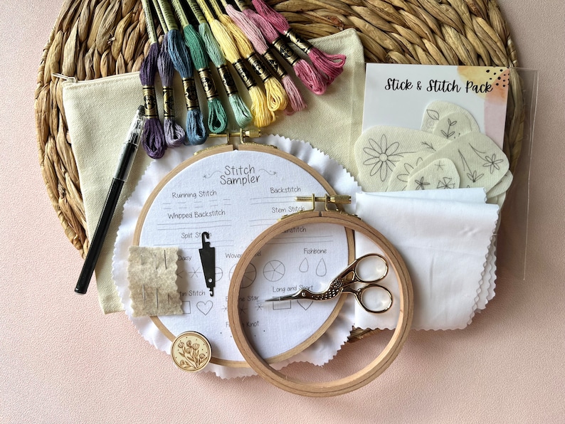 Puede incluir: Un kit de artesan&iacute;a para bordar con dos bastidores de bordado, un enhebrador de agujas, un par de tijeras, una peque&ntilde;a bolsa de hilo de bordar, un trozo de tela blanca, un trozo de tela beige, una peque&ntilde;a tarjeta con el texto "Stick & Stitch Pack" y una tarjeta con el texto "Stitch Sampler" con diferentes puntadas de bordado enumeradas.