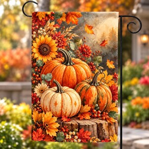 May include: A rectangular garden flag featuring a vibrant autumn scene with three pumpkins resting on a wooden log. The display includes bright orange sunflowers, red dahlias, scattered fall leaves, and clusters of small berries in warm tones.