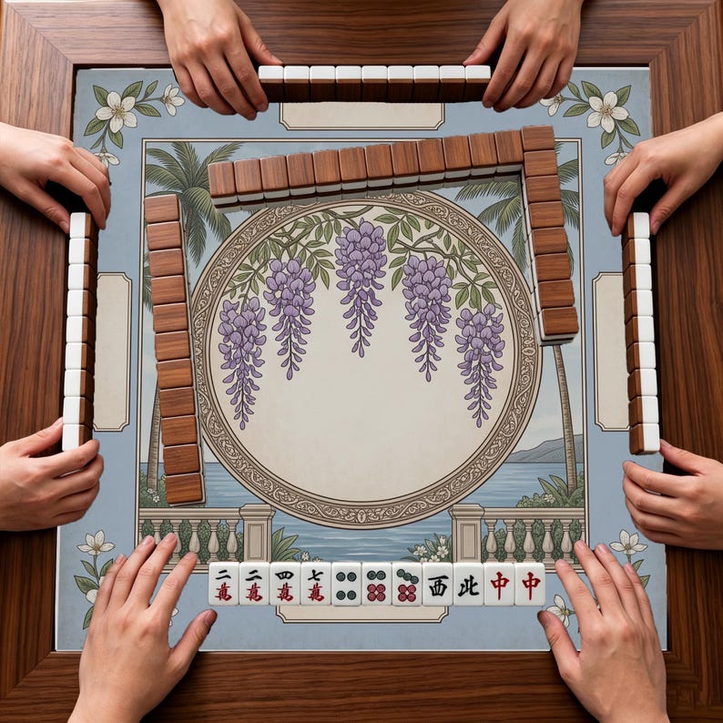 May include: A square mahjong table with a wooden frame featuring a central circular illustration of purple wisteria flowers. The game board displays a tropical landscape with palm trees and a balustrade. Rectangular mahjong tiles are arranged.