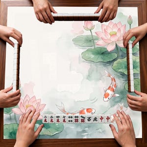 Puede incluir: Una mesa de mahjong cuadrada con un estampado estilo acuarela de flores de loto rosas, nen&uacute;fares verdes y peces koi naranjas y blancos. Cuatro filas de fichas de mahjong est&aacute;n dispuestas a lo largo de los bordes de la mesa.
