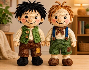 May include: Two handmade crochet dolls. One doll has black hair, a green vest, and brown shorts. The other doll has brown hair, blue suspenders, and green shorts. Both dolls have rosy cheeks and are smiling. The dolls are on a wooden surface.