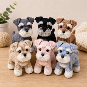 Könnte beinhalten: Sechs gehäkelte Schnauzer-Hundefiguren in verschiedenen Farben: Grau, Schwarz, Braun, Beige, Rosa und Blau. Jeder Hund hat einen weißen Bart und Augenbrauen, mit schwarzen Augen und einem kleinen Schwanz. Die Hunde sind auf einer Holzoberfläche angeordnet.