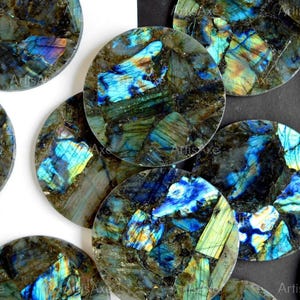 May include: A collection of round, polished labradorite stones. The stones display a mosaic of colors, including blues, greens, and yellows, with a dark gray base. The iridescent effect creates a shimmering, eye-catching appearance. The stones are ideal for jewelry making or decorative purposes.