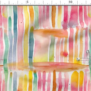 Peut inclure: Un tissu blanc avec un motif de rayures verticales à l'aquarelle dans des tons de rose, jaune, orange, vert et bleu. Une épingle à nourrice en métal est fixée sur le tissu, placé à côté d'une règle indiquant une mesure de 15 cm.