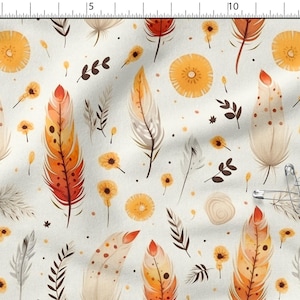 Könnte beinhalten: Ein Stoff mit einem sich wiederholenden Muster aus Federn im Aquarellstil in Orange-, Rot- und Cremetönen, zusammen mit kleinen gelben Blumen und Blättern auf hellbeigem Hintergrund. Das Design umfasst kleine braune Punkte und silberne Sicherheitsnadeln.