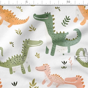 May include: White fabric with a repeating pattern of cartoon dinosaurs in orange, green, and pink. The dinosaurs have smiling faces and are interspersed with green and brown plant illustrations.