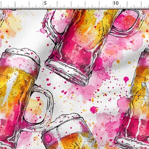 Puede incluir: Una tela blanca con un patrón repetitivo de jarras de cerveza llenas de líquido dorado y cubiertas con espuma blanca. El diseño incorpora salpicaduras y manchas de acuarela rosa y amarilla vibrantes por todo el fondo.