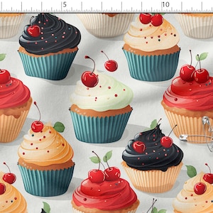 Può includere: Un motivo in tessuto con un design ripetuto di cupcake con glasse di vari colori, tra cui rosso, nero e crema, ognuno guarnito con ciliegie. Una spilla da balia è visibile sulla destra, accanto a un righello che misura 33 cm.