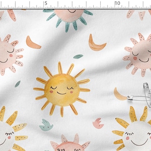 May include: White fabric with a repeating pattern of smiling suns, crescent moons, and small leaves in pastel colors. The suns are yellow, pink, and peach with closed eyes. The moons are a light orange.