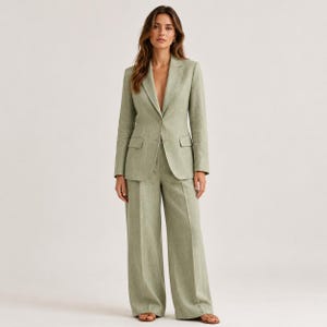 Könnte beinhalten: Ein salbeigrüner Zweiteiler bestehend aus einem einreihigen Blazer mit steigendem Revers, zwei Vordertaschen mit Patte und einem Knopfverschluss, kombiniert mit einer passenden Hose mit weitem Bein und gerader Schnittführung.