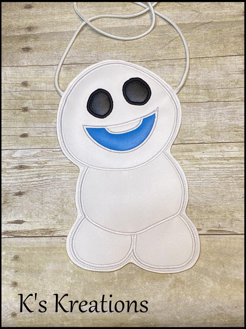 May include: A white crossbody bag shaped like a smiling snowman with black eyes and a blue mouth. The bag has a white cord strap and the text "K's Kreations" at the bottom.