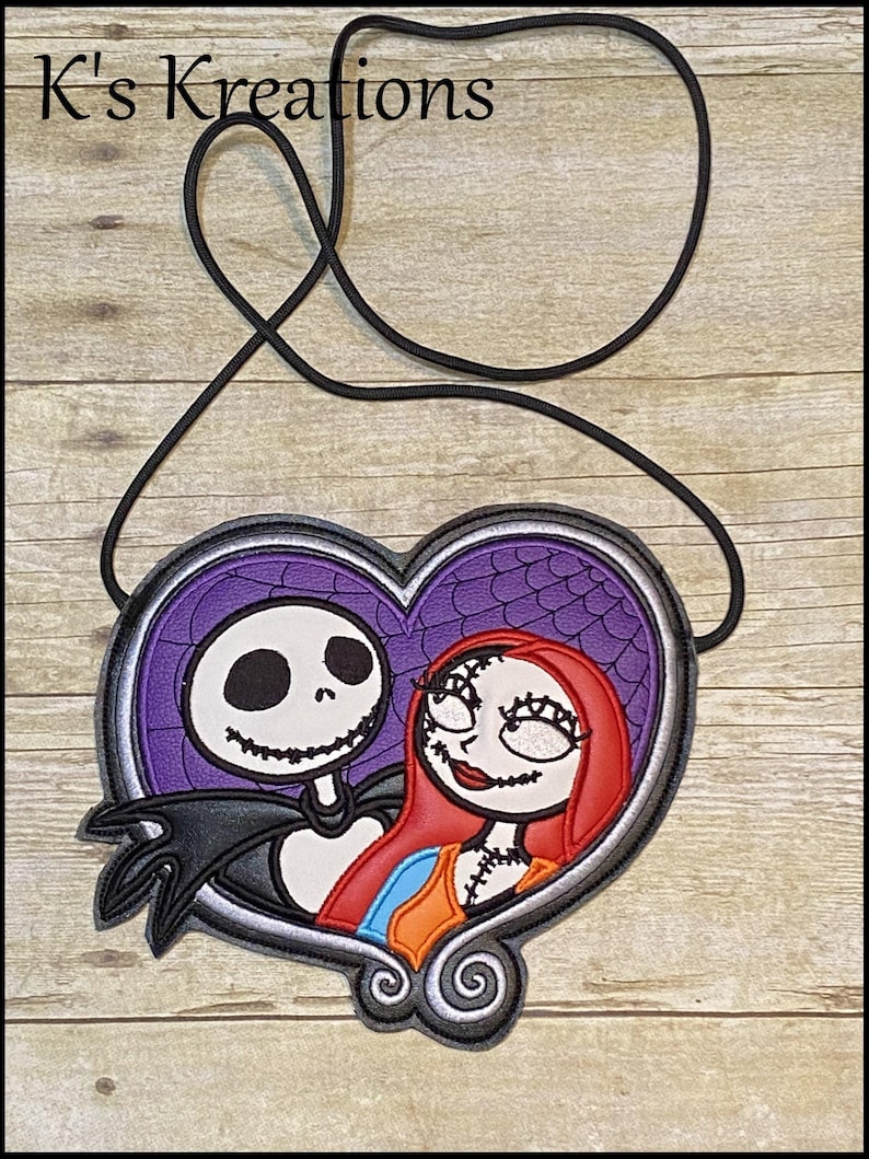 May include: A heart-shaped lanyard featuring Jack Skellington and Sally from The Nightmare Before Christmas. The design has a purple background with a spiderweb pattern, and a black cord. The text "K's Kreations" is at the top.
