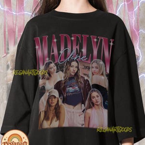Peut inclure: Un sweat-shirt noir à col rond arborant une grande impression graphique de Madelyn Cline. Le motif comprend le nom MADELYN CLINE en lettres roses audacieuses, plusieurs portraits photographiques de l'actrice et un fond avec des éclairs.