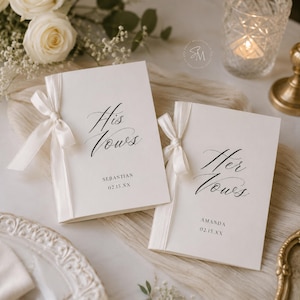 Pode incluir: Dois livretos de votos em tom branco sujo com caligrafia preta. Um diz His Vows com o nome Sebastian e a data 02.15.XX, o outro Her Vows com o nome Amanda e a data 02.15.XX. Cada livreto é amarrado com uma fita de cetim branca.