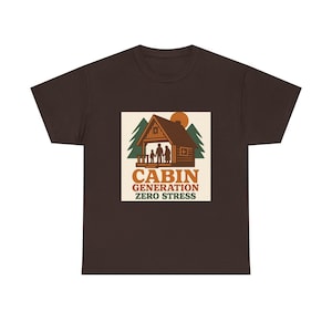 Peut inclure: T-shirt marron foncé avec un motif de cabane, une famille, des arbres et un soleil. Le texte "CABIN GENERATION ZERO STRESS" est en dessous. Le t-shirt est fait d'une matière douce.