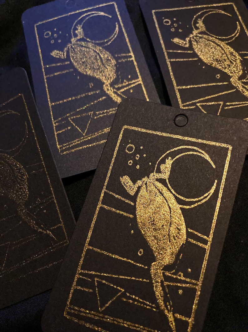 May include: Four black cards with gold foil accents. Each card features a stylized illustration of a creature with a crescent moon in the background. The creature is depicted in a gold foil design.