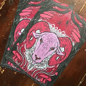 Puede incluir: Un carnero rosa con grandes cuernos est&aacute; rodeado de setas rojas y blancas y una telara&ntilde;a negra sobre un fondo negro.