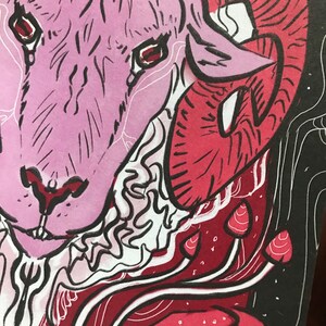 Puede incluir: Una ilustraci&oacute;n de una cabeza de carnero en rosa y rojo, con un cuerno grande y rizado. La cara del carnero est&aacute; detallada con l&iacute;neas negras y ojos rojos. El fondo es negro con setas rojas y blancas.