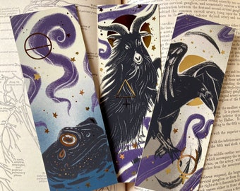 May include: Set of five bookmarks featuring black and white illustrations of a goat, a raven, a frog, and two abstract designs. The bookmarks have a purple and gold background with stars.