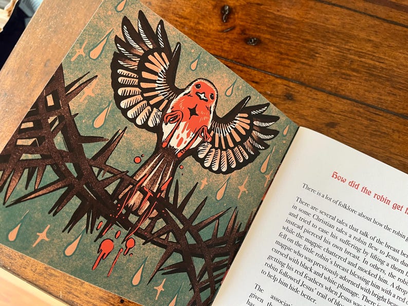 May include: A red robin perched on a thorny branch with blood dripping from its beak. The illustration is in a vintage style with a green background and gold stars. The text reads "How did the robin get its red breast?"