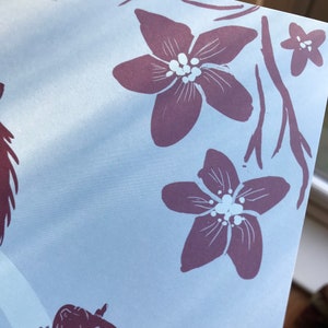 May include: A close-up of a light blue background with a purple floral design. The flowers have white centers and are arranged in a cluster at the top right corner of the image.