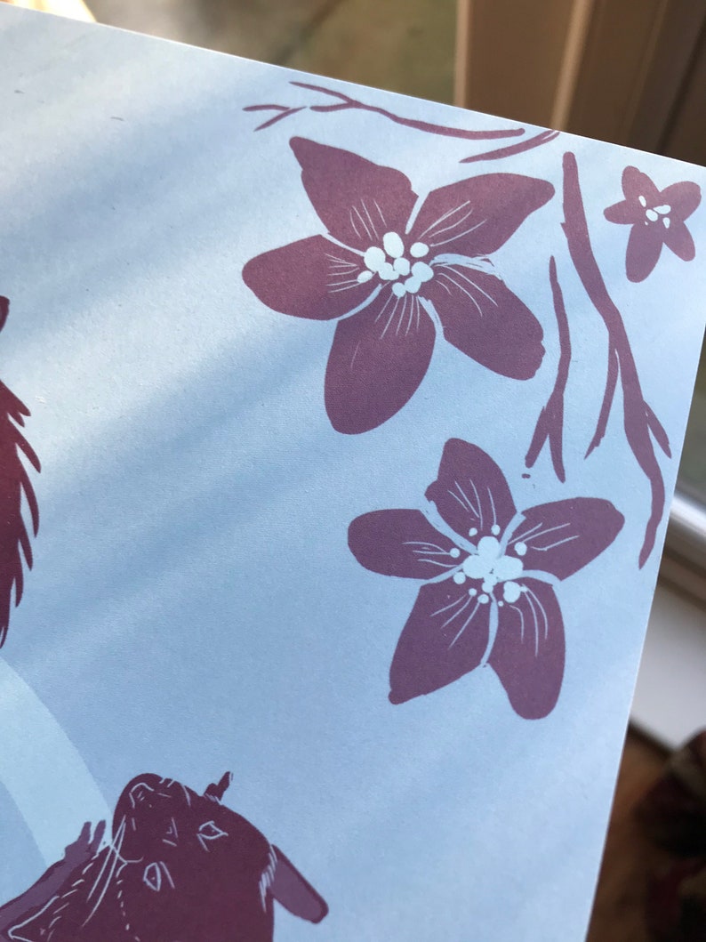 May include: A close-up of a light blue background with a purple floral design. The flowers have white centers and are arranged in a cluster at the top right corner of the image.