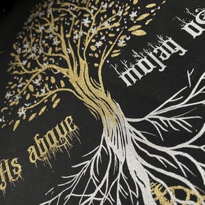 May include: A black t-shirt with a gold and silver glitter design of a tree with the text "As above so below" and "majesty" on either side of the tree.