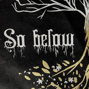 May include: Black canvas tote bag with white and gold paint. The bag features a stylized tree with roots and branches, and the words "So below" in white paint.