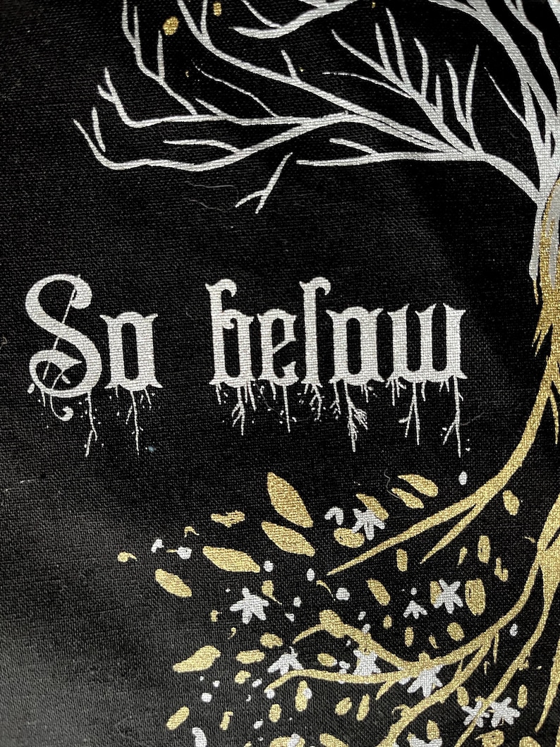 May include: Black canvas tote bag with white and gold paint. The bag features a stylized tree with roots and branches, and the words "So below" in white paint.