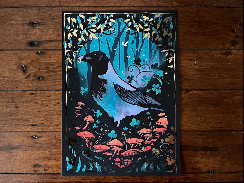 Puede incluir: Un cuervo azul y negro con un pico amarillo posado en un entorno de bosque. El cuervo est&aacute; rodeado de hojas verdes y setas rosas. El fondo es azul oscuro con detalles dorados.
