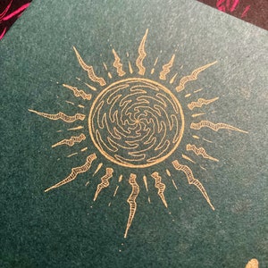Puede incluir: Un sol dorado con un patr&oacute;n de remolino en su interior y un fondo verde texturizado.