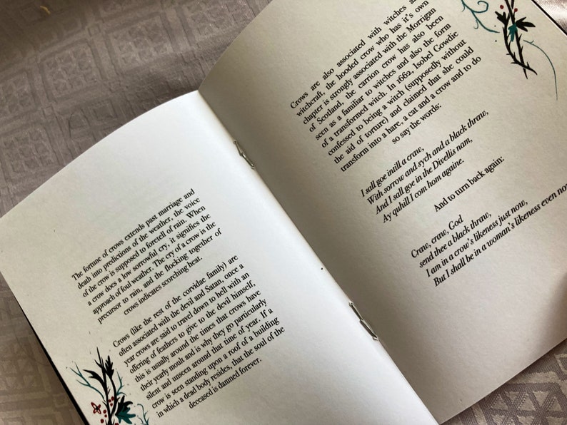 May include: Open book with white pages and black text. The text discusses the folklore and symbolism of crows. The book is open to a page with the text "I sall goe intill a craw, With sorrow and sych and a black thraw, And I sall goe in the Divellis nam, Ay quhill I com hom againe. And to turn back again:"