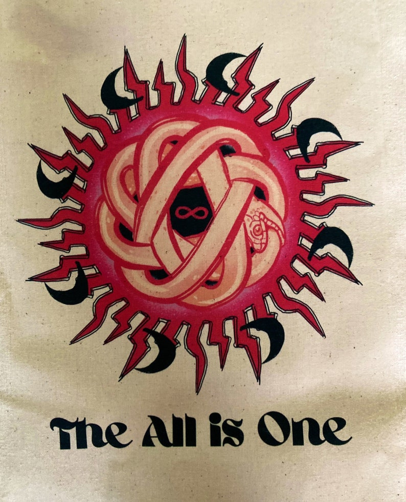 May include: A beige tote bag with a red and black sun design and the text "The All is One" printed in black below the sun.