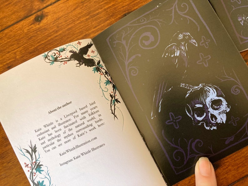 May include: An open book with a black and white illustration of a raven and a skull on the right page. The left page has text about the author, Katie Whittle, a Liverpool-based bird enthusiast and illustrator. The text mentions her fascination with folklore and mythology, particularly surrounding birds. The book's cover features a decorative border with vines and flowers.