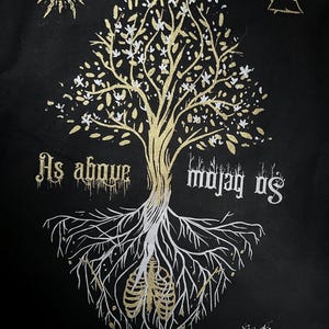 May include: A black background with a gold tree with white flowers and roots. The tree has a gold sun above it and a gold triangle above the tree. The roots are white and have a gold ribcage in the center. The text "As above so below" is written in gold on the left side of the tree and the text "So below as above" is written in gold on the right side of the tree.