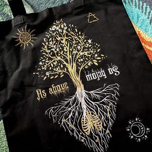 May include: Black tote bag with a gold tree design and the text "As above so below" and "maya us".