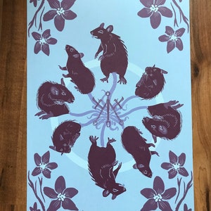 May include: A blue background with a circle of eight black rats in various poses. The rats are arranged around a central symbol of three swords. The background is decorated with purple flowers.
