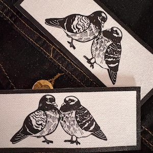 May include: A white ceramic mug with a black handle and the text "But First, Coffee" in a bold, black font. The mug is set against a blurred background, suggesting a cozy setting.