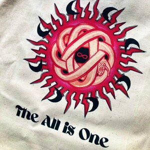 May include: A white tote bag with a red and black graphic of a snake wrapped around a sun with the text "The All is One" printed below.