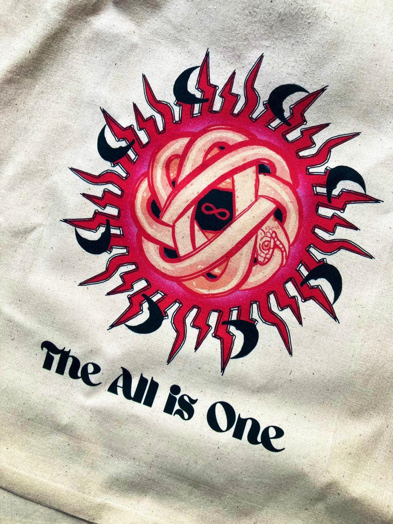 May include: A white tote bag with a red and black graphic of a snake wrapped around a sun with the text "The All is One" printed below.