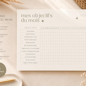 May include: A printable monthly goals planner with the text "mes objectifs du mois" in a minimalist design. The planner includes a grid for tracking daily progress and a list of goals. The color scheme is beige and brown.