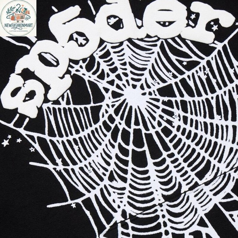 K&ouml;nnte beinhalten: Schwarzer Stoff mit einem wei&szlig;en Spinnennetz-Design und dem Wort "Spider" in einer aufgebl&auml;hten, wei&szlig;en Schriftart. Das Design enth&auml;lt kleine Sterne. Das Bild ist eine Nahaufnahme des Stoffes.
