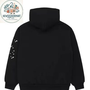 K&ouml;nnte beinhalten: Schwarzer Kapuzenpullover mit hohem Kragen und wei&szlig;em Sternmuster auf dem linken &Auml;rmel. Der Hoodie hat eine Kapuze mit Kordelzug und eine K&auml;ngurutasche. Das NewFashionMart-Logo befindet sich oben links.