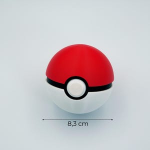 Puede incluir: Una Poké Ball roja y blanca, una esfera con una banda negra y un botón blanco. La bola mide aproximadamente 8,3 cm de diámetro. La mitad superior es roja y la mitad inferior es blanca.