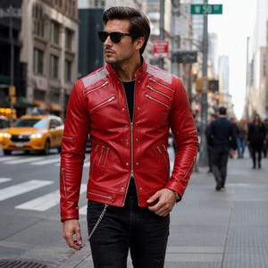 May include: A vibrant red leather jacket featuring a mandarin collar, multiple silver-toned diagonal zippered pockets, and textured silver shoulder panels. The jacket has a central full-length zipper closure and is paired with black denim jeans.